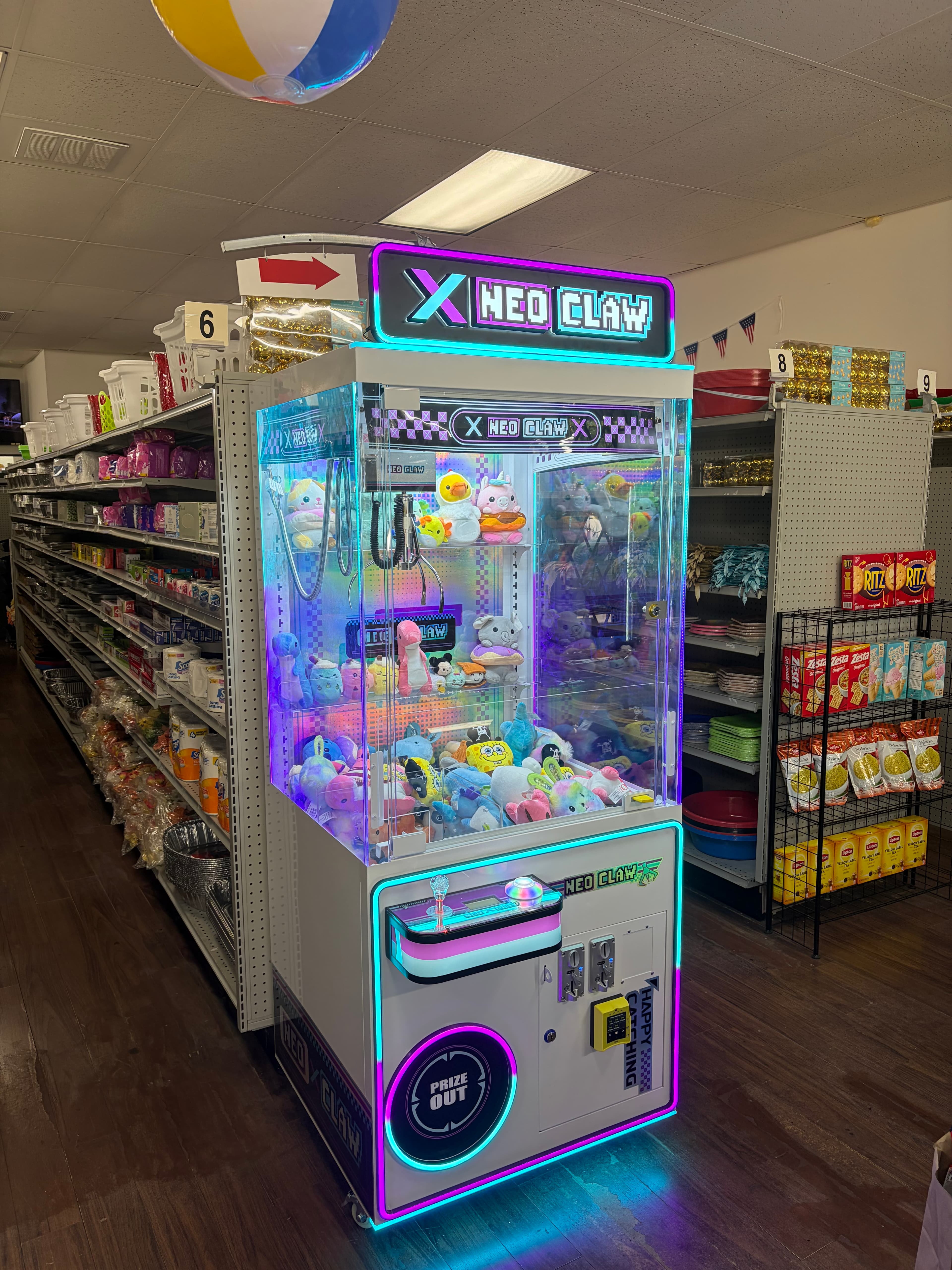 Neon-lit Neo Claw crane machine filled with colorful plush toys in a store aisle.